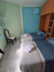a room with three beds and a chair in it at Casa Nasarre- Acogedora casa rural con garaje con vistas a la Sierra de GUARA in Abiego