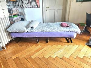 a bed sitting on top of a wooden floor at Lake apartment with terrace in Nidau