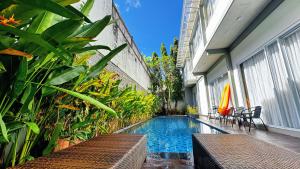 a swimming pool with tables and chairs next to a building at Cozy Guest House Canggu in Kerobokan
