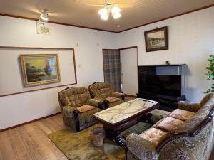 a living room with couches and a table and a tv at AppleHouse高瀬駅 in Mitoyo