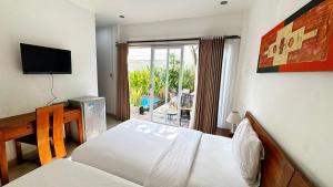 a bedroom with a bed and a tv and a window at Cozy Guest House Canggu in Kerobokan