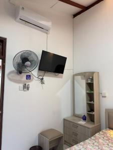 a bedroom with a tv and a fan on the wall at Hantana Villa in Kandy