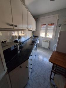 a kitchen with white cabinets and a black counter top at Casa Nasarre- Acogedora casa rural con garaje con vistas a la Sierra de GUARA in Abiego +14 photos