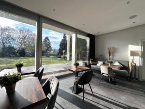ein Wohnzimmer mit Tischen und Stühlen und einem großen Fenster in der Unterkunft Hotel Bevertal in Beverungen