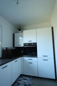 a kitchen with white cabinets and a black microwave at Wasser & Bergwelt Appartement Kärnten in Seeboden +21 photos