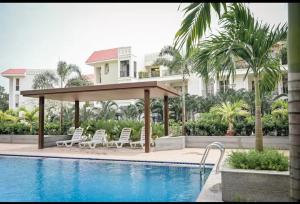 a pool with chairs and a gazebo next to a house at Bella casa in Siolim