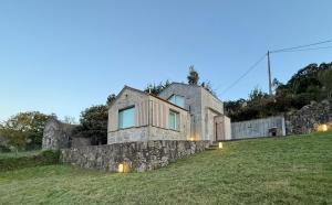 a house on a hill with a stone wall at Lar do Mar in Beloso