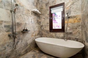 a bath tub in a bathroom with a window at Little Town Villa in Hoi An