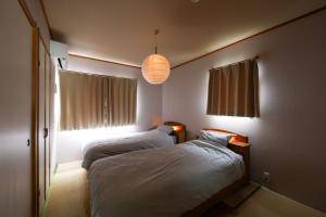 a bedroom with two beds and a lamp and windows at Nagoya Kuwana Choco House in Yatomi 