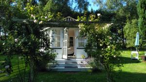 a small white house with a porch and roses at Romantik og idyl in Dybvad