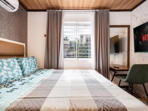 a bedroom with a bed and a desk and a window at Bella Casa (3BR House at Azienda Genova) in Talisay