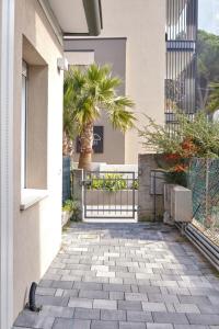 a walkway outside a building with a gate and palm trees at Beach 300m Piazza Milano in Lido di Jesolo