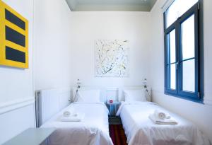 アテネにあるNeoclassical House at Metro Station Attikiの白い壁と窓が備わる客室で、ベッド2台が備わります。