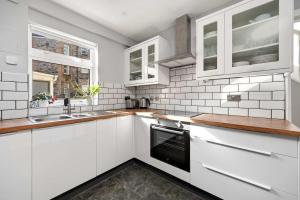 a kitchen with white cabinets and a sink at 4-Bed Home Central Location & Garden in Oban