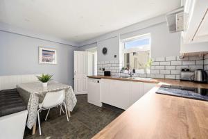 a kitchen with white cabinets and a table and a sink at 4-Bed Home Central Location & Garden in Oban