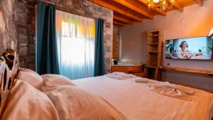 a bedroom with a bed with a tv and a window at Tetka Konukevi in Ayvalık