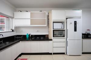 a white kitchen with white cabinets and a refrigerator at Sobrado Jardim Real in Maringá +10 photos