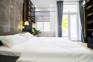 a bedroom with a large white bed and a window at An Nhiên House in Kon Rung (1)