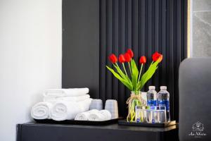 a table with red flowers in a vase and towels at An Nhiên House in Kon Rung (1)