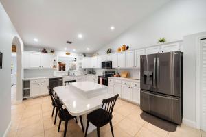 a kitchen with a table and a stainless steel refrigerator at Spacious 5BR Pool Oasis Near Disney Resort in Sebastian +25 photos