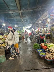 a group of people in a market with fruits and vegetables at La Maison de My Tho in Mỹ Tho