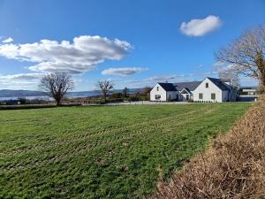 a large field with two white houses in the distance at Lakeview farm in Castletown