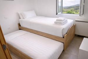 two beds in a small room with a window at Nova MSuites Xove in Lago