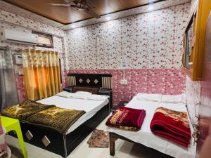 two beds in a room with pink wallpaper at Jagdamba home stay in Ayodhya