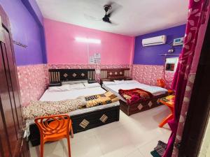 two beds in a room with pink and purple walls at Jagdamba home stay in Ayodhya