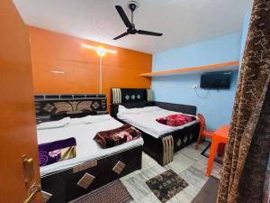 a room with two beds and a tv in it at Jagdamba home stay in Ayodhya