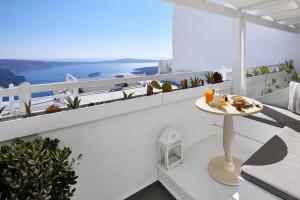 a white balcony with a table with drinks on it at Santorini Roses Suites in Imerovigli