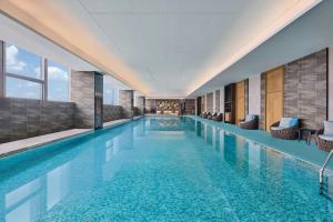 a large swimming pool with blue water in a building at Four Points by Sheraton Wuhan, Jiangxia in Wuhan