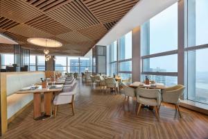 a restaurant with tables and chairs and large windows at Four Points by Sheraton Wuhan, Jiangxia in Wuhan