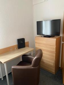 a room with a desk and a chair and a television at Pension Zum Angestellten in Porta Westfalica +30 photos