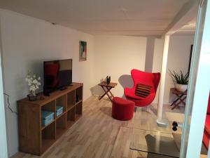 a living room with a television and a red chair at Gamle Præstegård, viceværtlejlighed in Årup