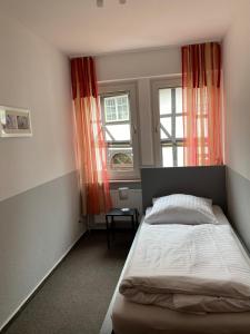 a bedroom with a bed and two windows at Pension Zum Angestellten in Porta Westfalica