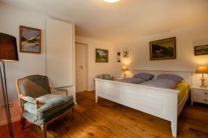 a bedroom with a white bed and a chair at Danielenhof1701, Ferienwohnung Bruckbach in Breitnau +12 photos