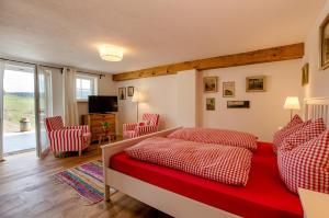 a bedroom with a red bed and two red chairs at Danielenhof1701, Ferienwohnung Bruckbach in Breitnau