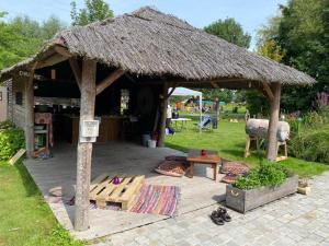 a pavilion with a grass roof and a picnic table at Ferme de la Naverie wi - holiday home for 2 persons in Celles
