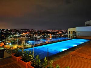 a large swimming pool on the roof of a building at night at 222 at Maine in Pretoria
