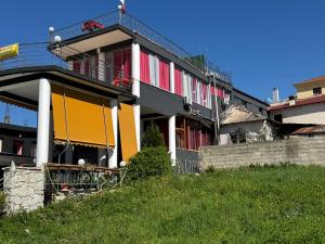 a building with red and yellow windows on a hill at Hotel Bar Restaurant Mete in Peshkëpi