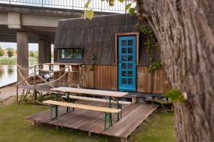 a house with a blue door and benches on a dock at Glampervan Rietje in Den Bosch