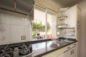 a kitchen with white cabinets and a sink and a window at Casa Outeiro in Encinedo +16 photos