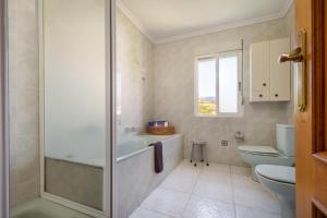 a bathroom with a tub and a toilet and a sink at Casa Outeiro in Encinedo