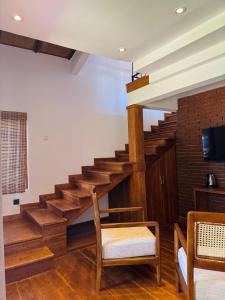 a living room with wooden stairs and a television at Aria Resort in Sigiriya