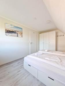a white bedroom with two beds and a painting on the wall at Strandkrabbe in Greetsiel
