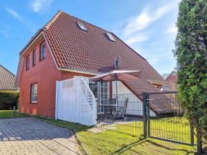 a house with a fence and an umbrella in the yard at Strandkrabbe in Greetsiel