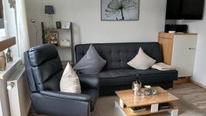 a living room with a black leather couch and a table at Ferienwohnung Sommerwind in Willingen