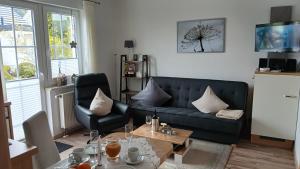 a living room with a black couch and a table at Ferienwohnung Sommerwind in Willingen
