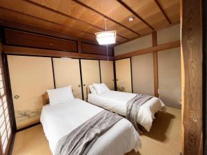 two beds in a room with wooden walls at Tani House Tokiwa Nozawa Onsen & More in Iiyama